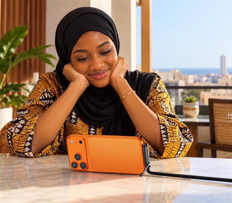 Femme regardant une vidéo sur son téléphone posé sur le support pliant, sur une terrasse à Dakar